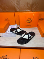 Black thong sandals with white strap panels and square logo buckle, one pair angled