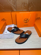 Black leather sandals with brown sole, open-toe thong strap design on display
