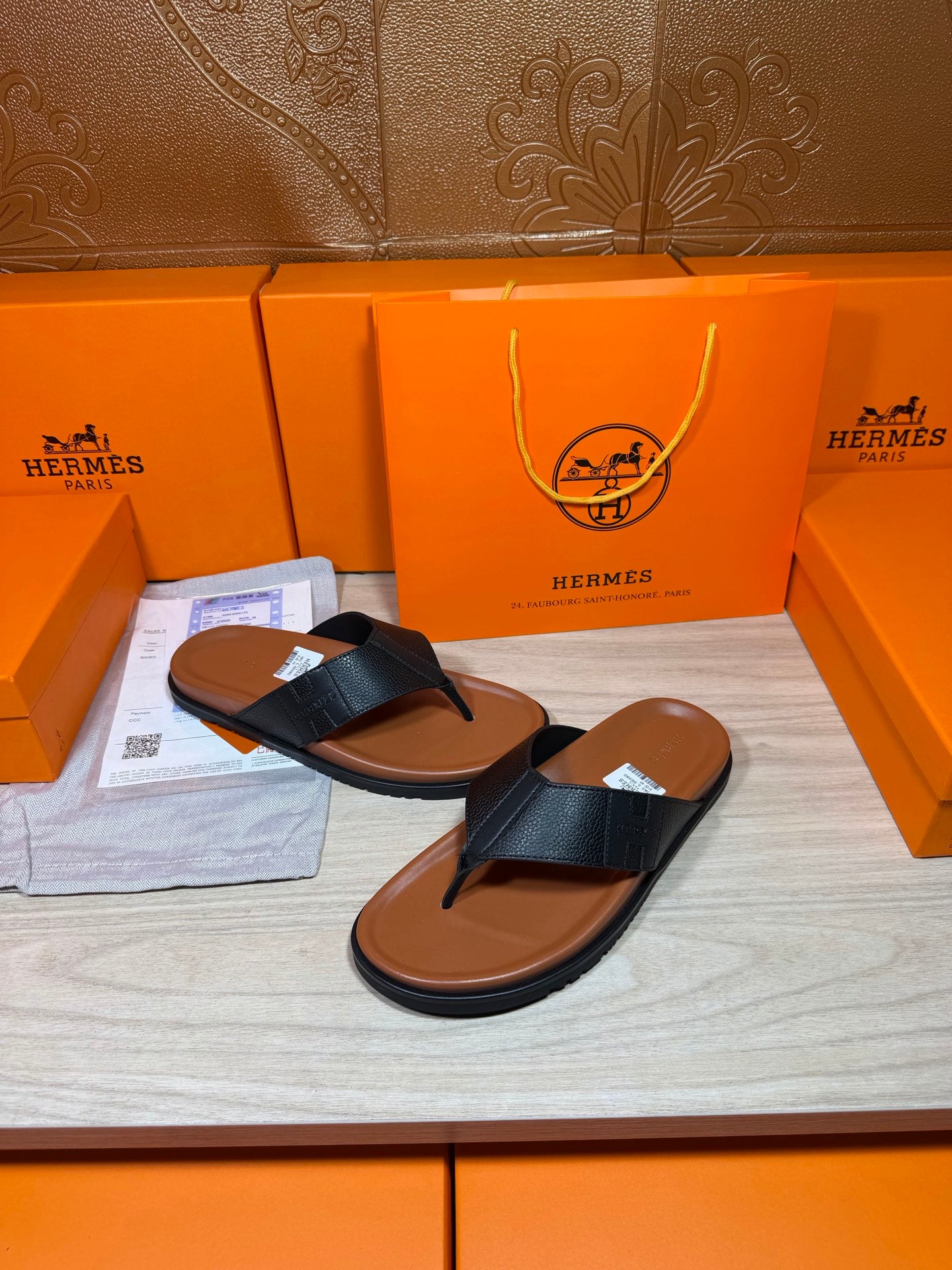 Black leather sandals with brown sole, open-toe thong strap design on display