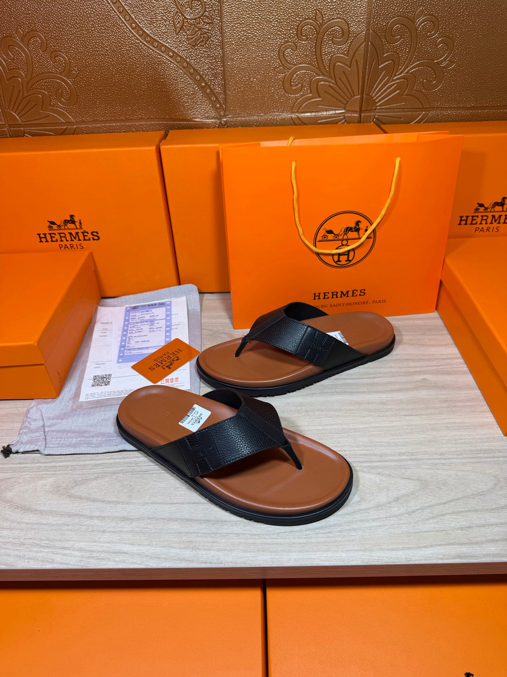 Black leather thong sandals with brown rubber sole, side-by-side on display surface