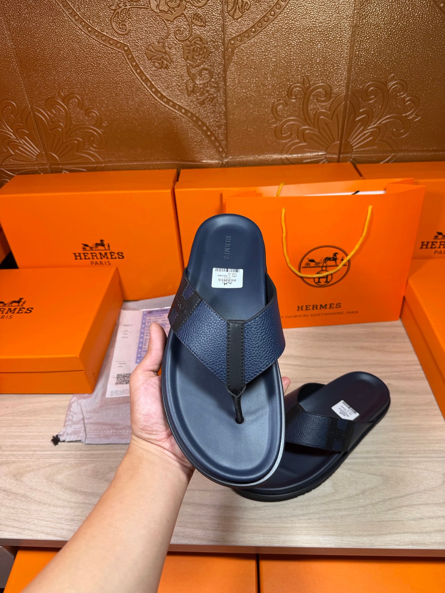 Hermes dark blue leather thong sandals shown with one sandal in hand