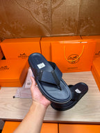 Hermes dark blue leather sandals held in hand, textured thong strap