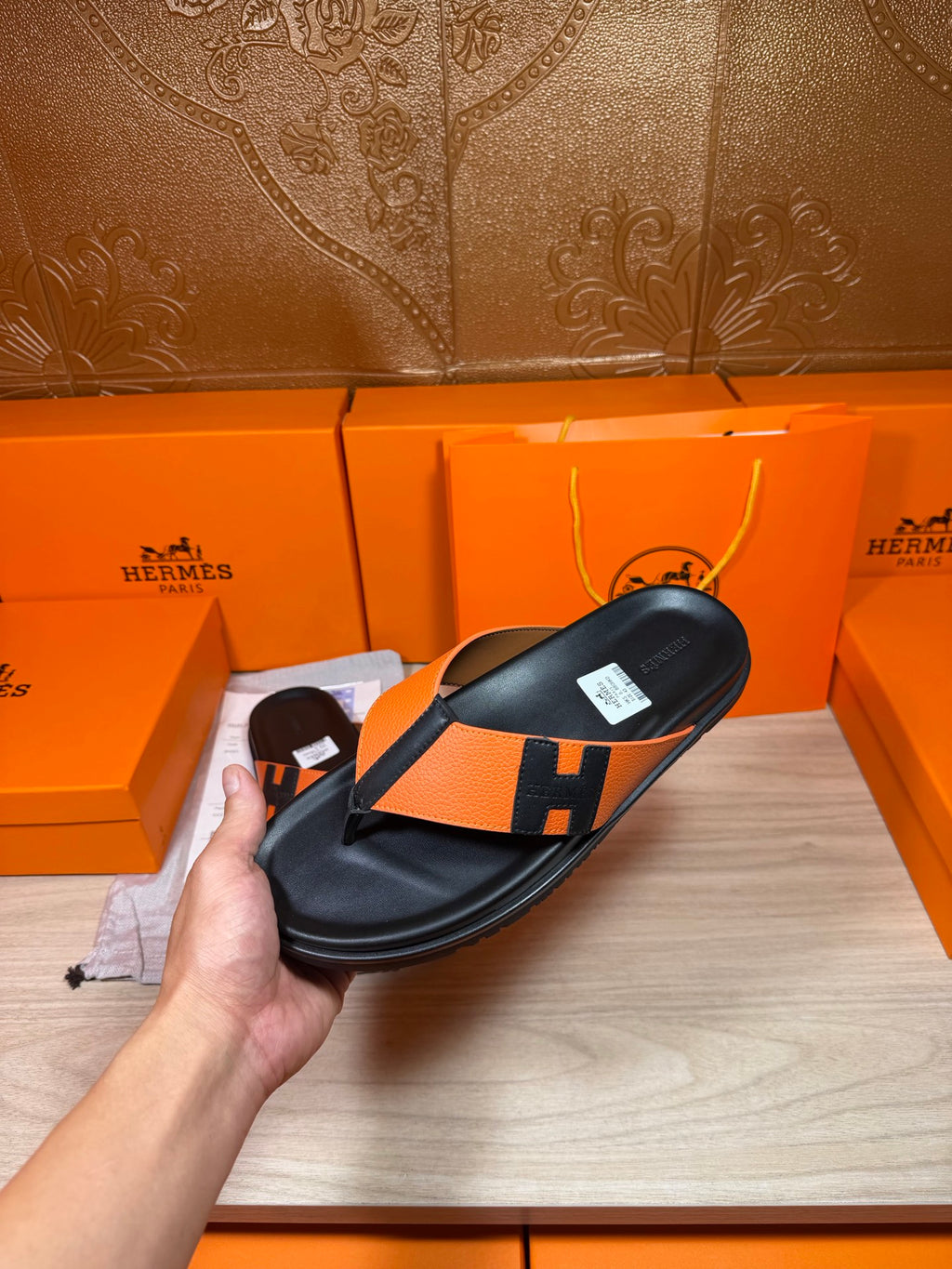 Single black-and-orange H logo slide sandal with thong strap, flat.