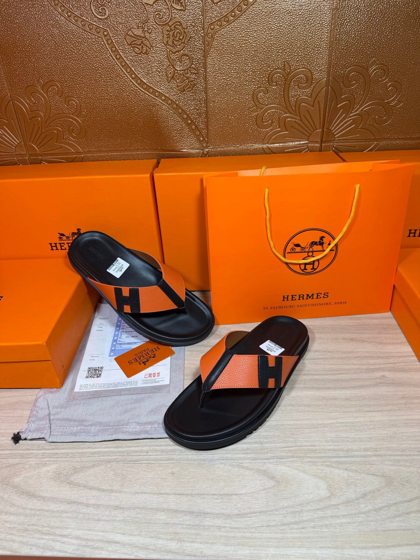 Two-tone orange and black H sandals with black thong straps, flat slip-on.