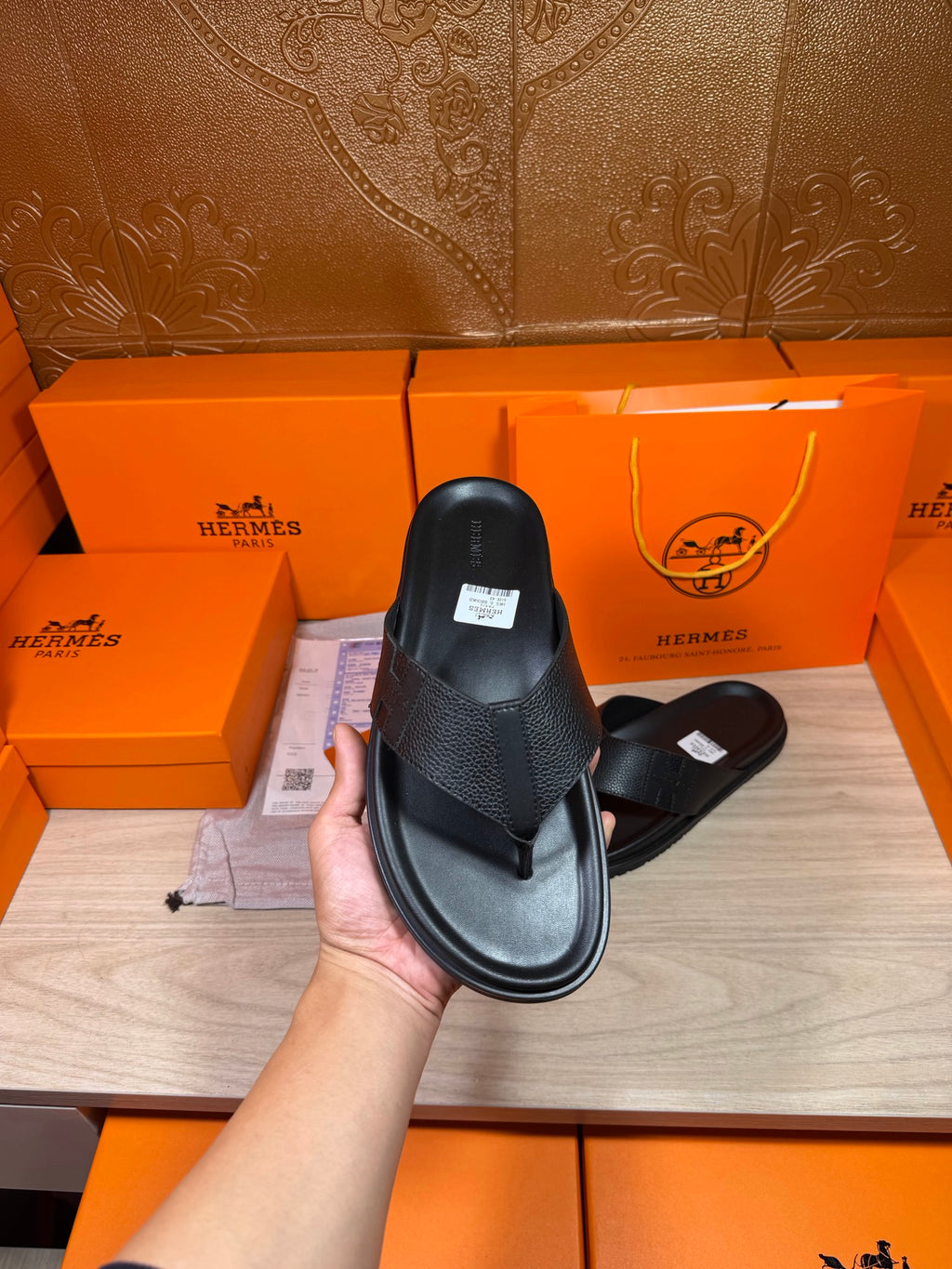 Hermes black leather slide sandals held up with cross strap and flat sole.