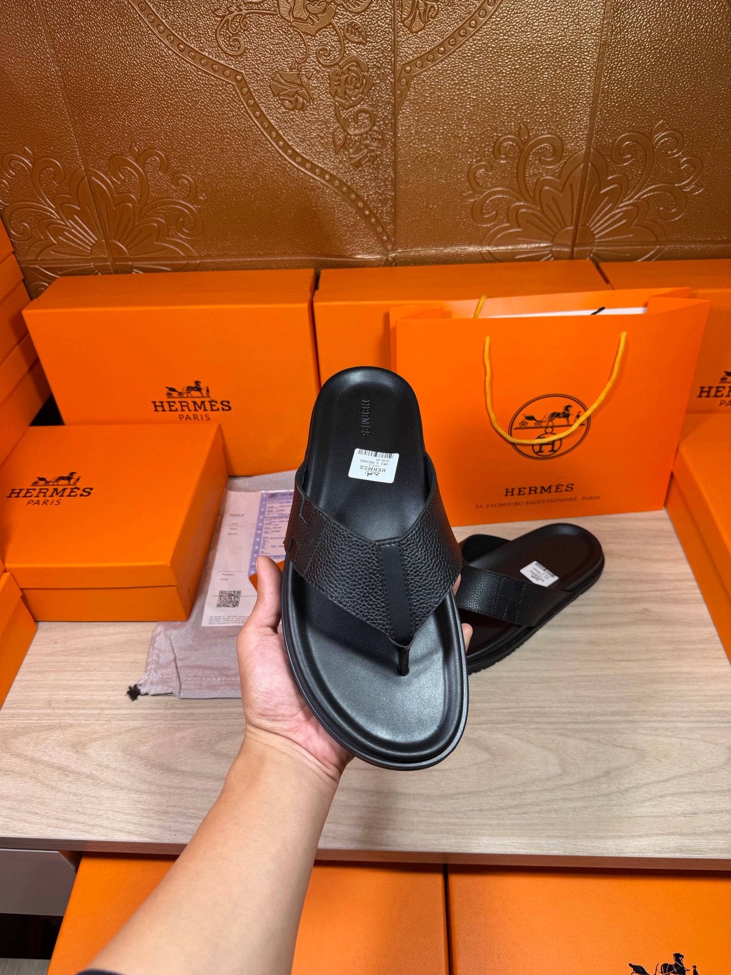Hermes black leather slide sandals held up with cross strap and flat sole.