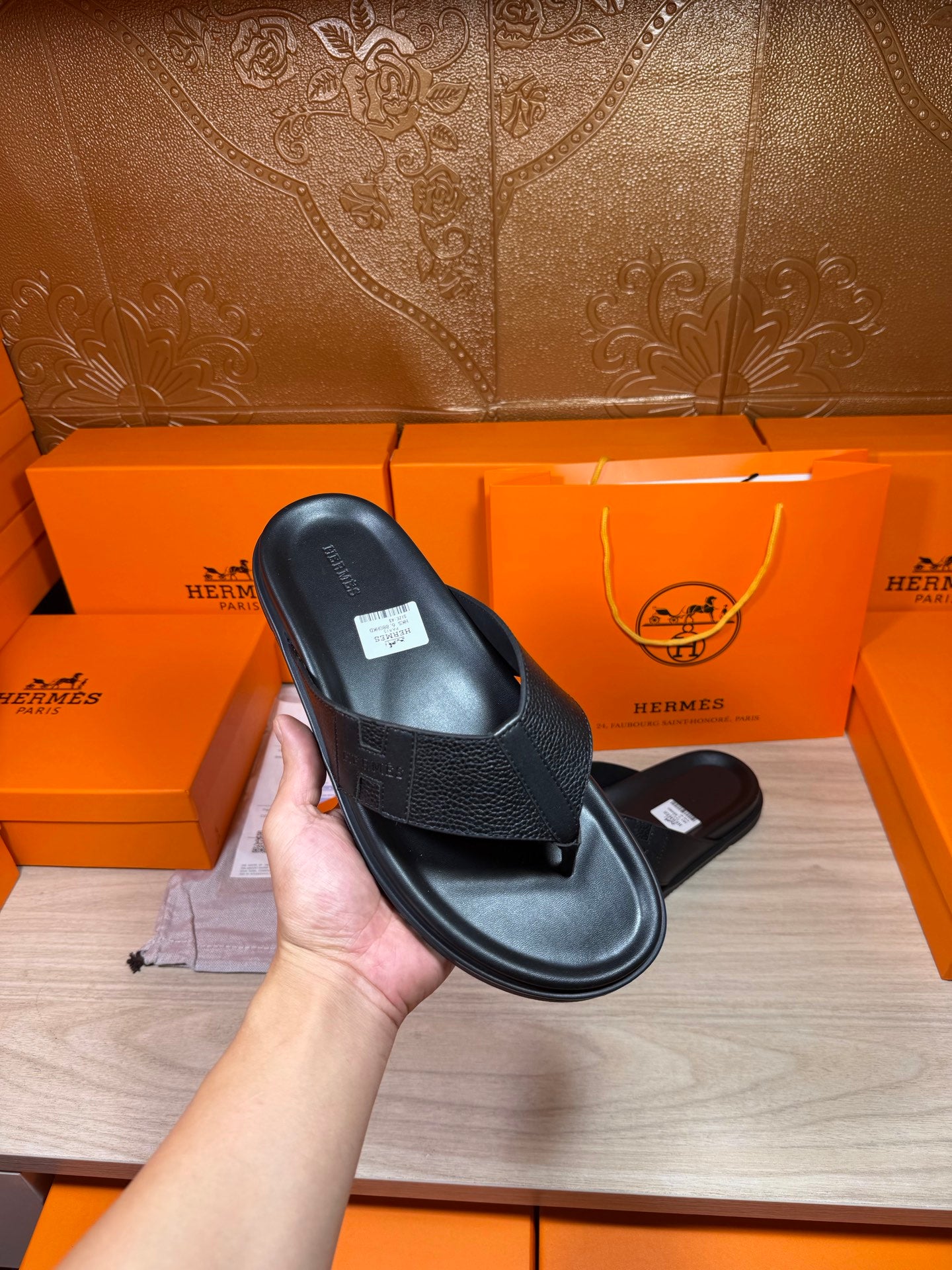 Hermes black leather slide sandals close-up of upper strap and flat rubber sole.