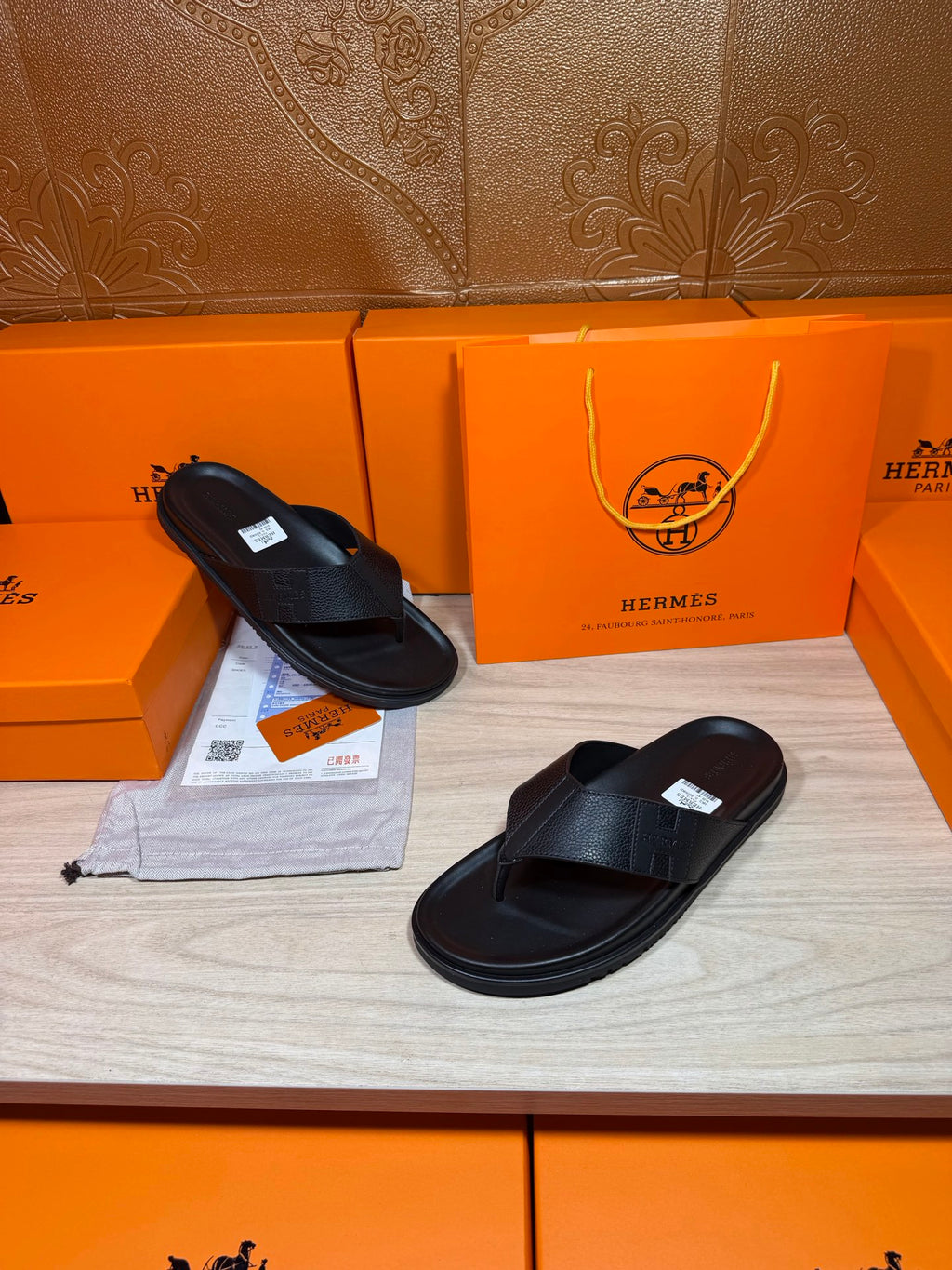 Hermes black leather slide sandals with molded footbed and flat rubber sole.