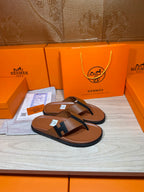Pair of brown leather thong sandals with dark H strap and flat rubber sole