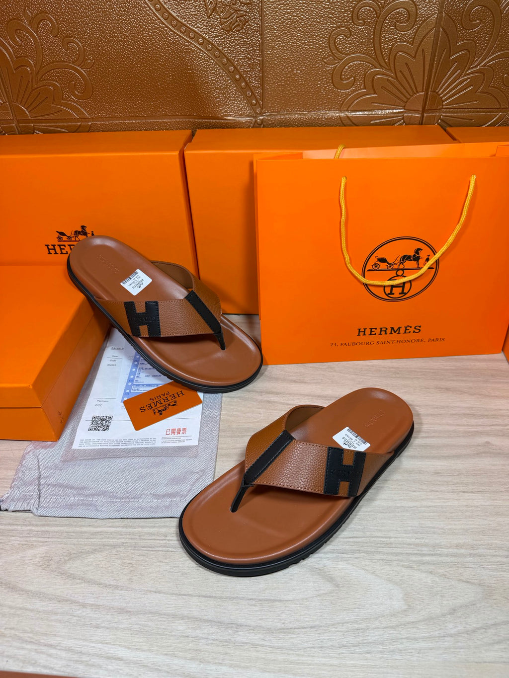 Two brown leather thong sandals with dark H strap, flat soles and toe posts