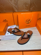 Brown leather flip-flop sandals with dark H strap and thong-style toe post