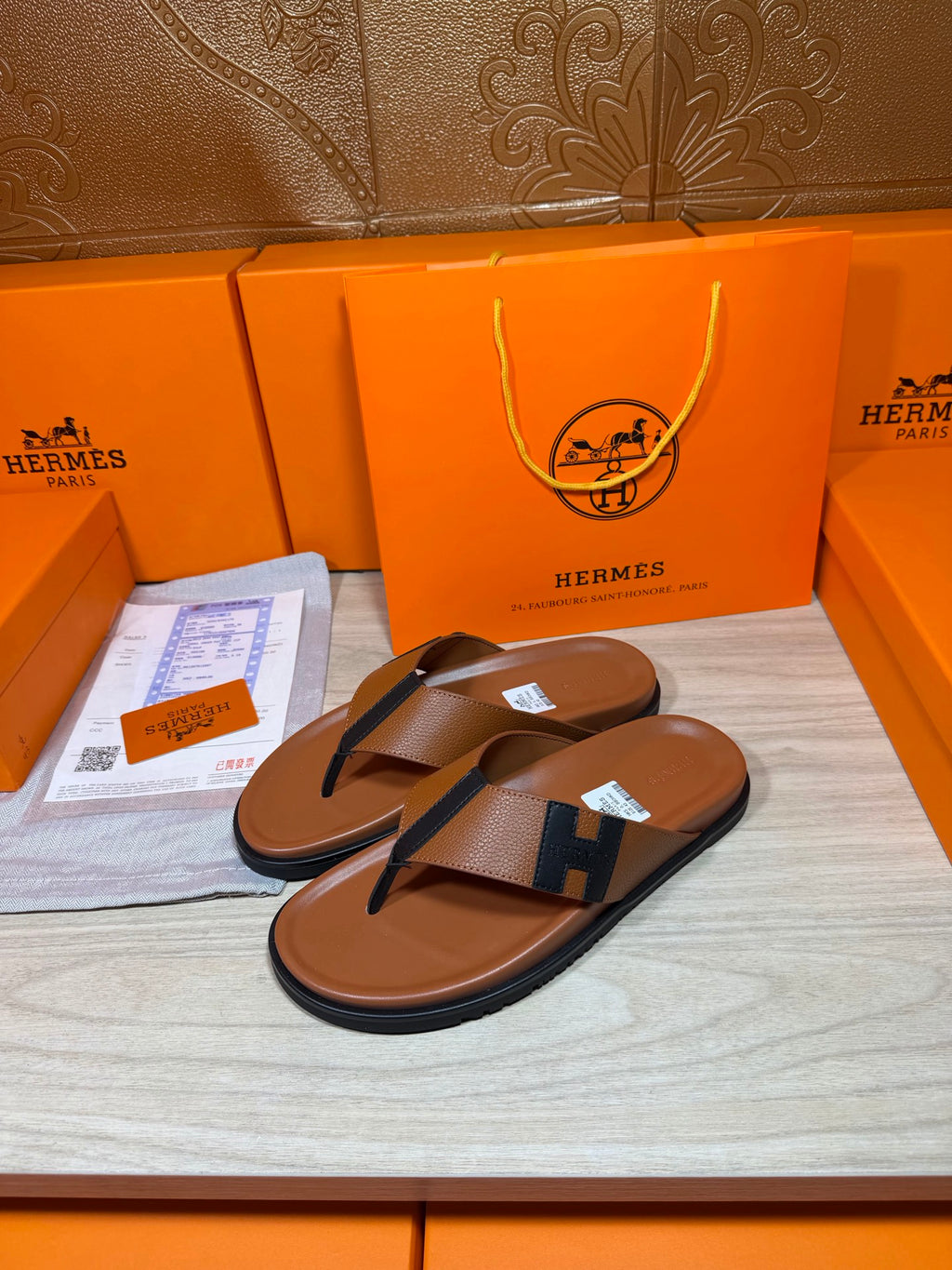 Brown leather thong sandals with dark blue H strap detail and textured footbeds