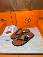 Brown leather thong sandals with dark blue H strap detail and textured footbeds