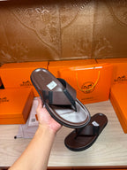 Dark leather flip-flop held in hand with black strap and flat sole