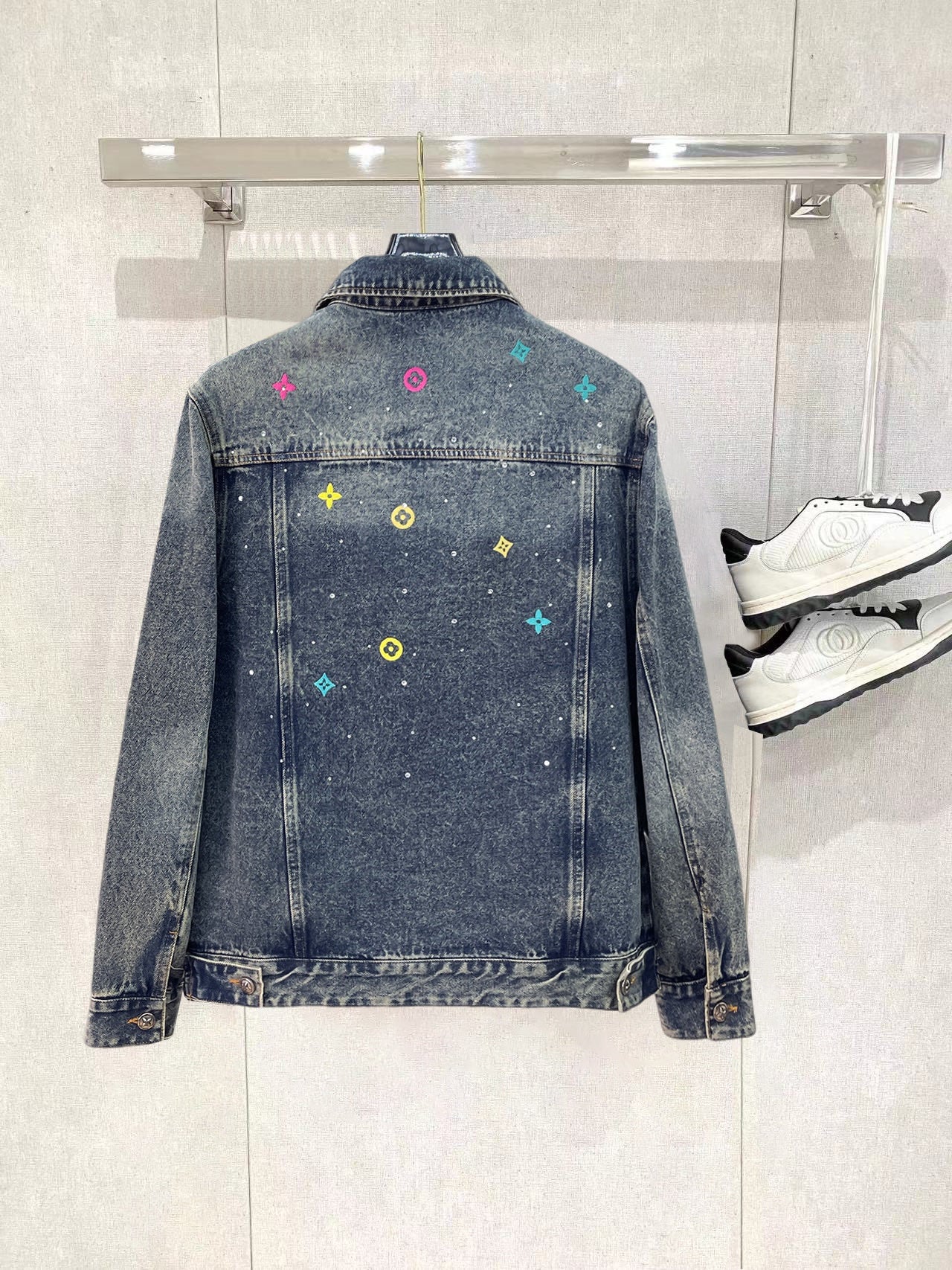 Denim jacket back panel with button closure and scattered multicolor logo patches