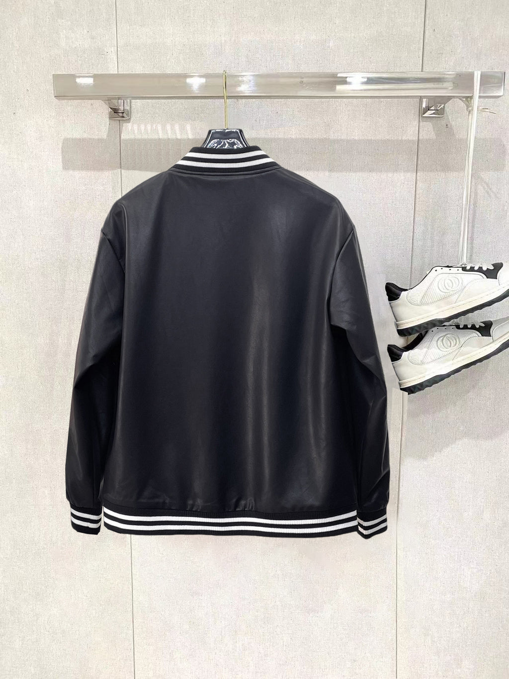 Black leather bomber jacket back view with striped ribbed collar and hem