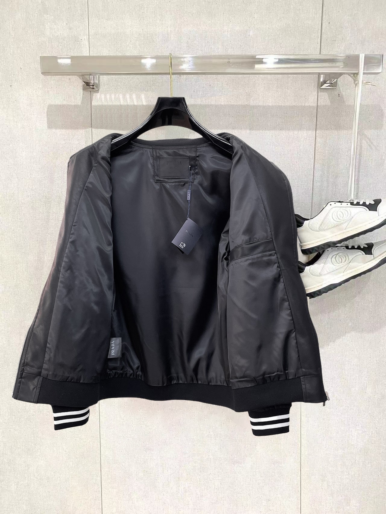 Black leather bomber jacket with open front showing lining and zippered pocket