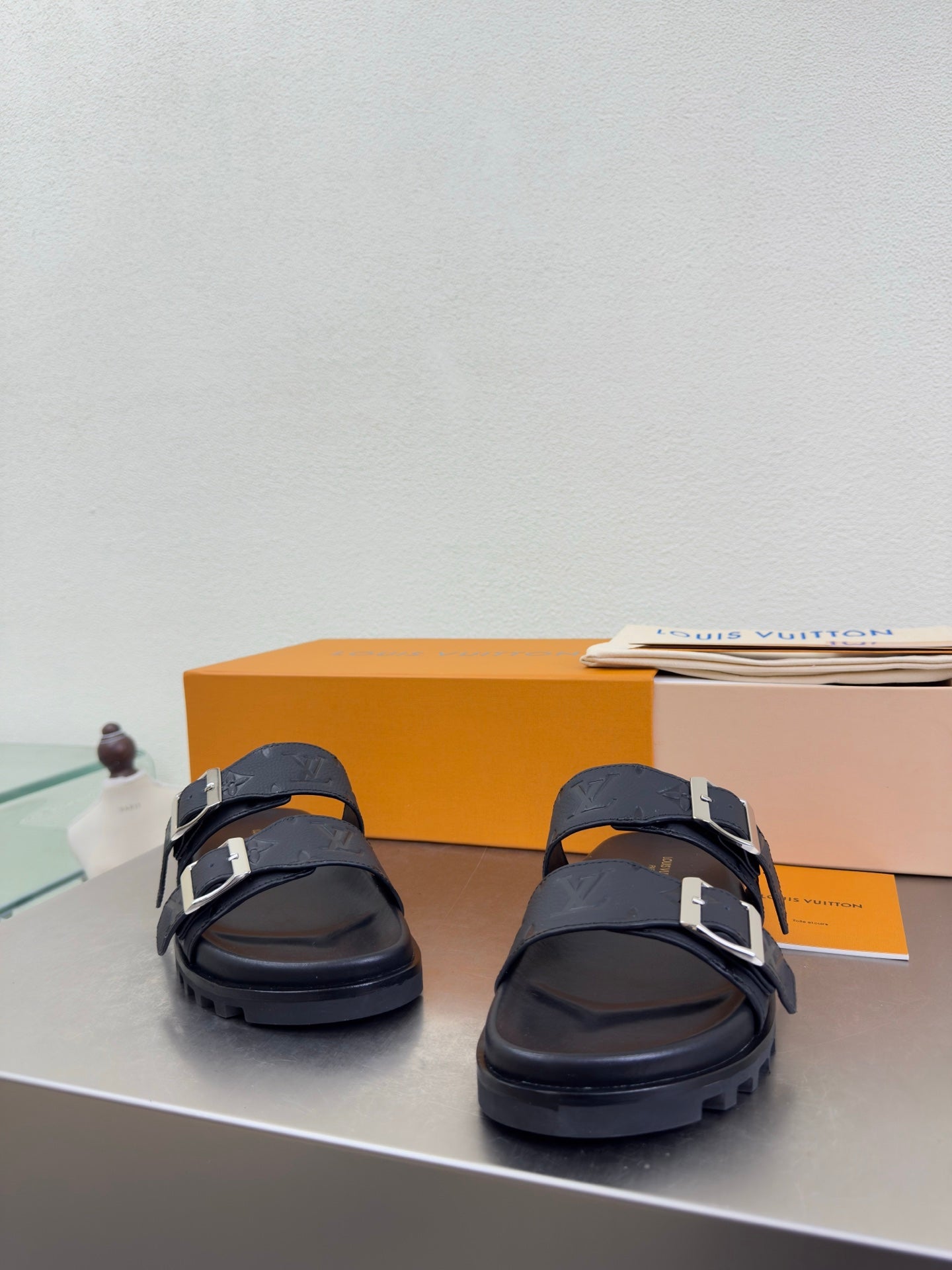 Louis Vuitton sandals shown from front with dark straps and silver buckle details