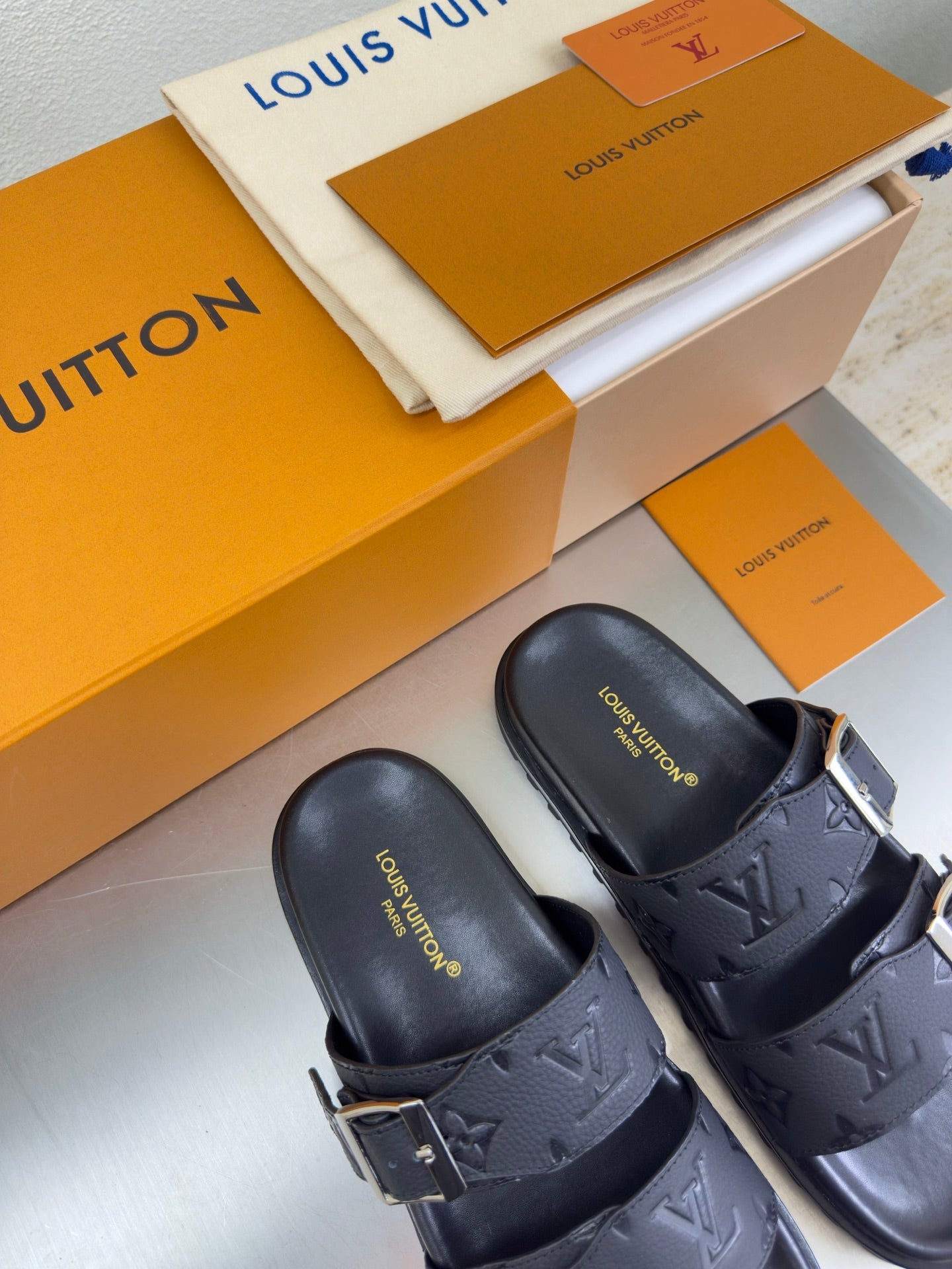 Louis Vuitton sandals featuring dark leather straps with LV monogram and silver buckles