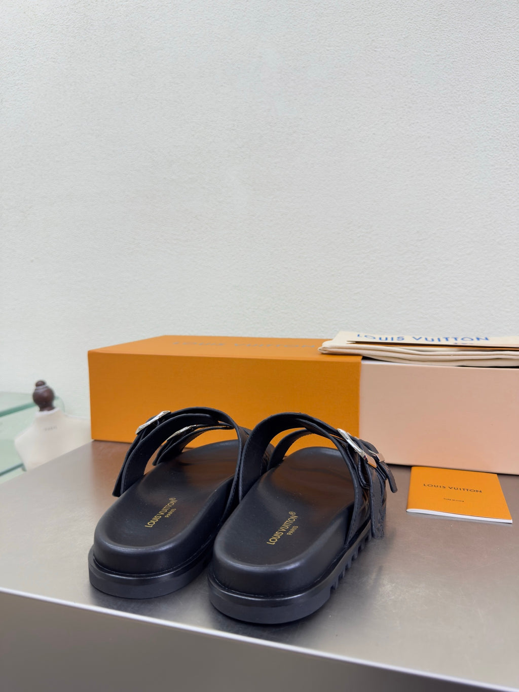 Louis Vuitton slide sandals with dark straps and silver buckle hardware over an open toe