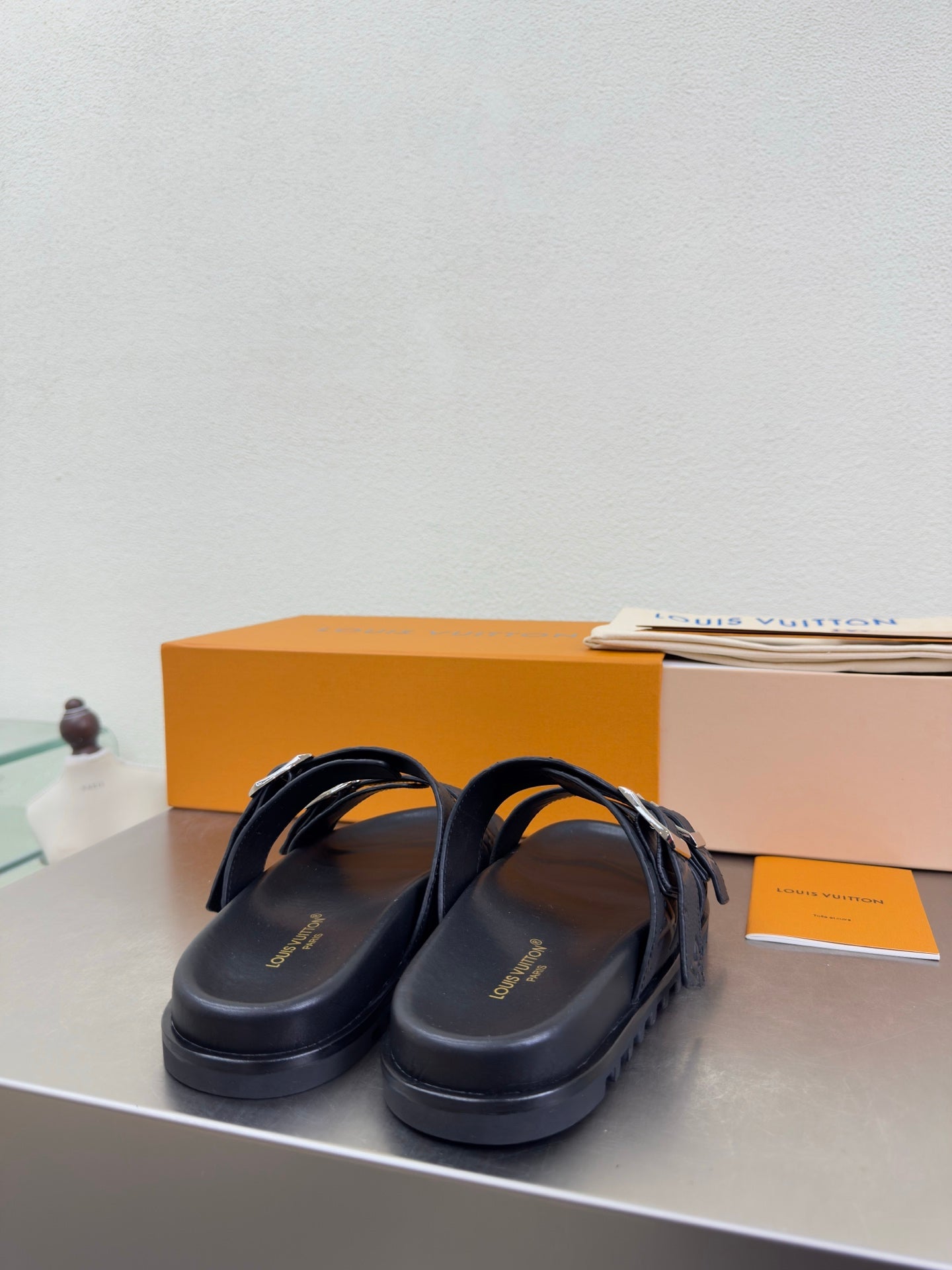 Louis Vuitton slide sandals with dark straps and silver buckle hardware over an open toe
