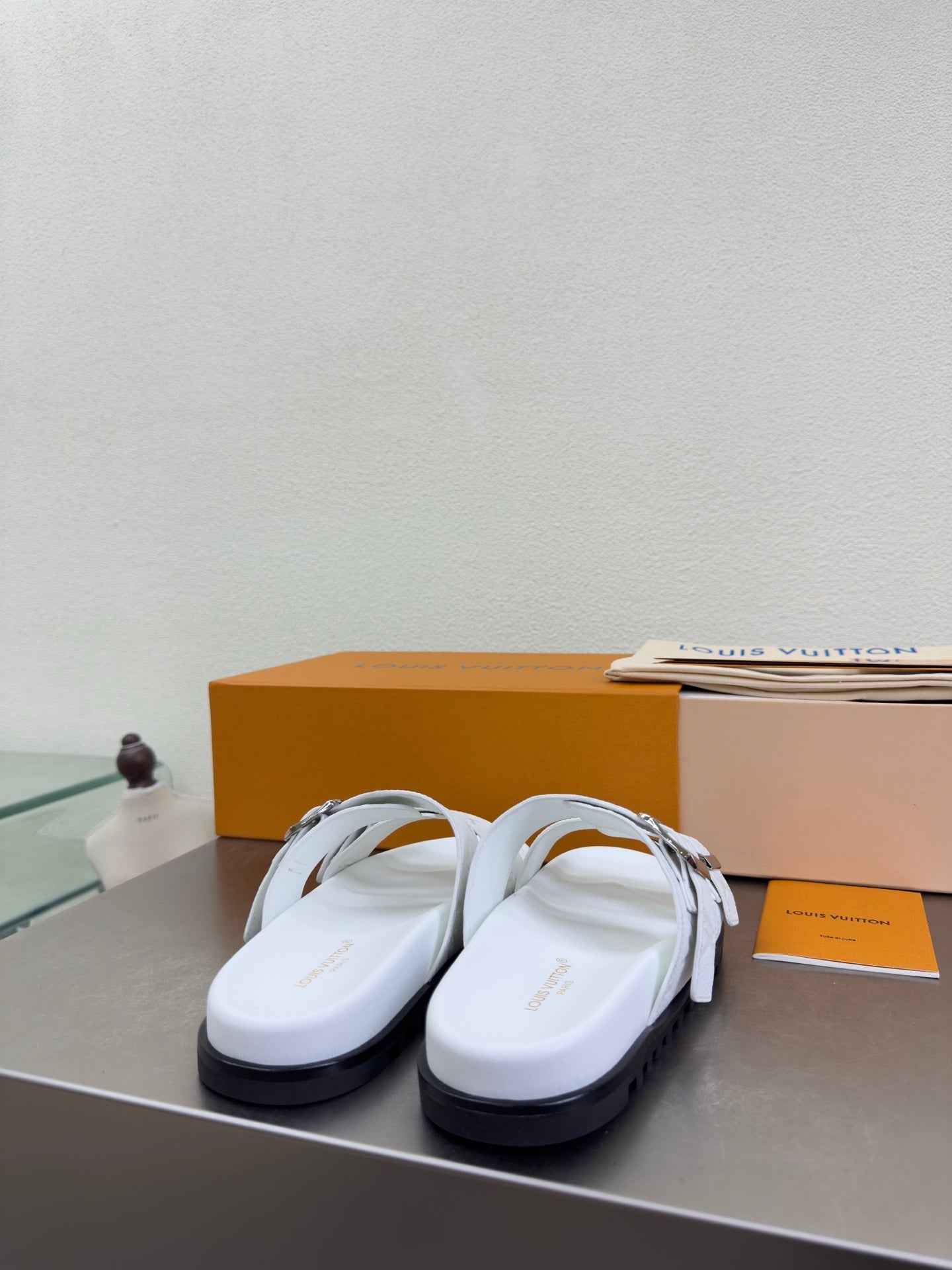 White Louis Vuitton sandals with wide straps, silver buckles, and side profile