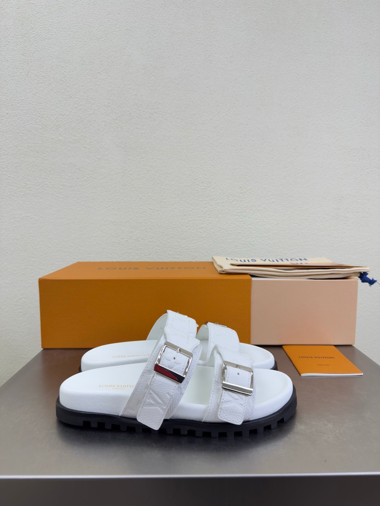 White Louis Vuitton sandals with two front buckle straps and thick dark tread