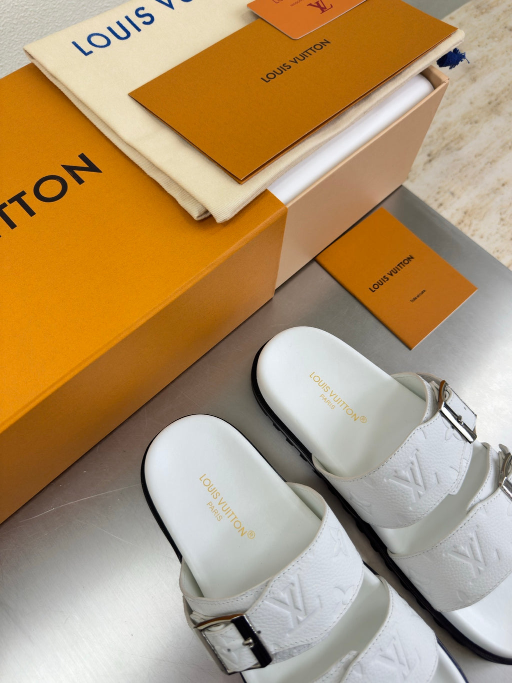 White Louis Vuitton buckle sandals, close-up on embossed straps and textured sole