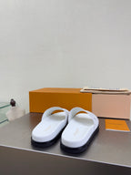 White monogram slide sandals with wide strap and dark tread sole