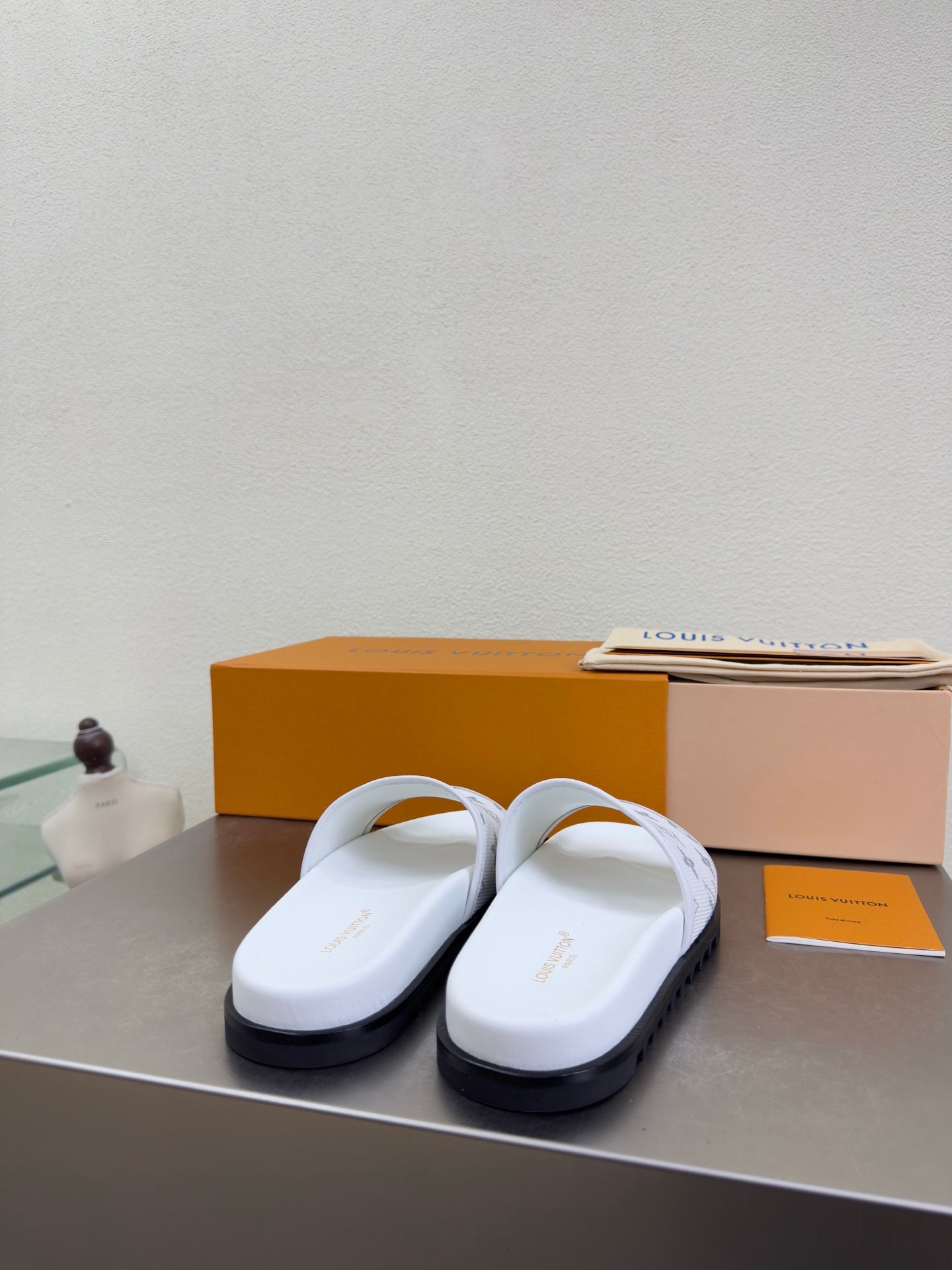 White monogram slide sandals with wide strap and dark tread sole