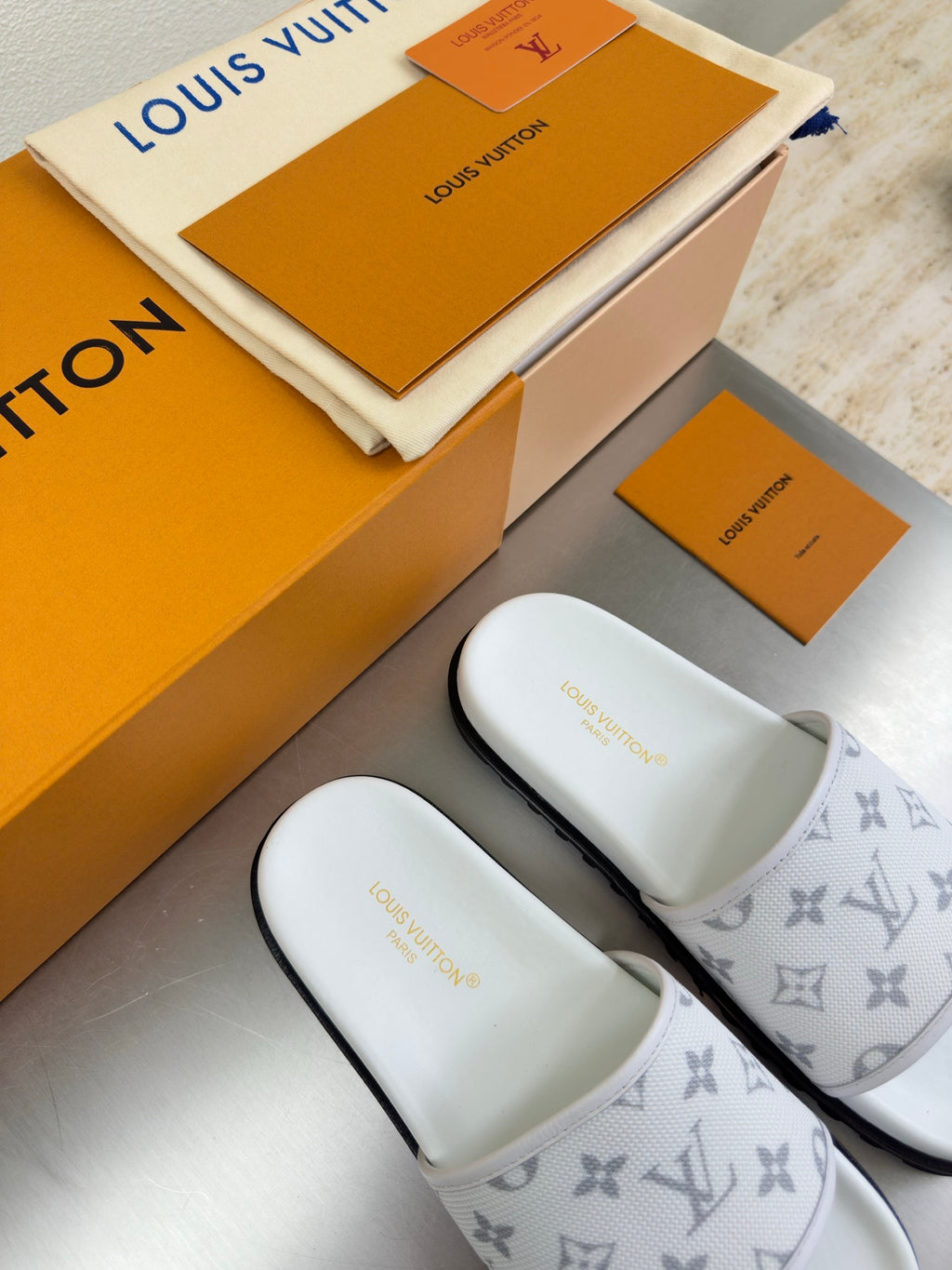 White monogram slide sandals, two pairs shown on display