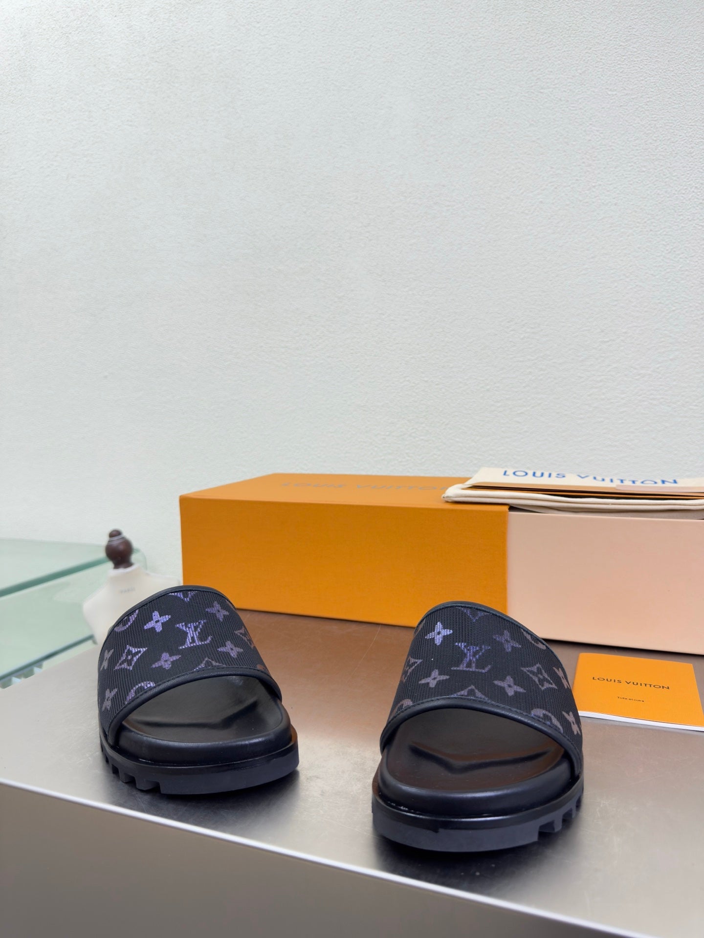Louis Vuitton slide sandals with dark upper and blue monogram pattern, rear view