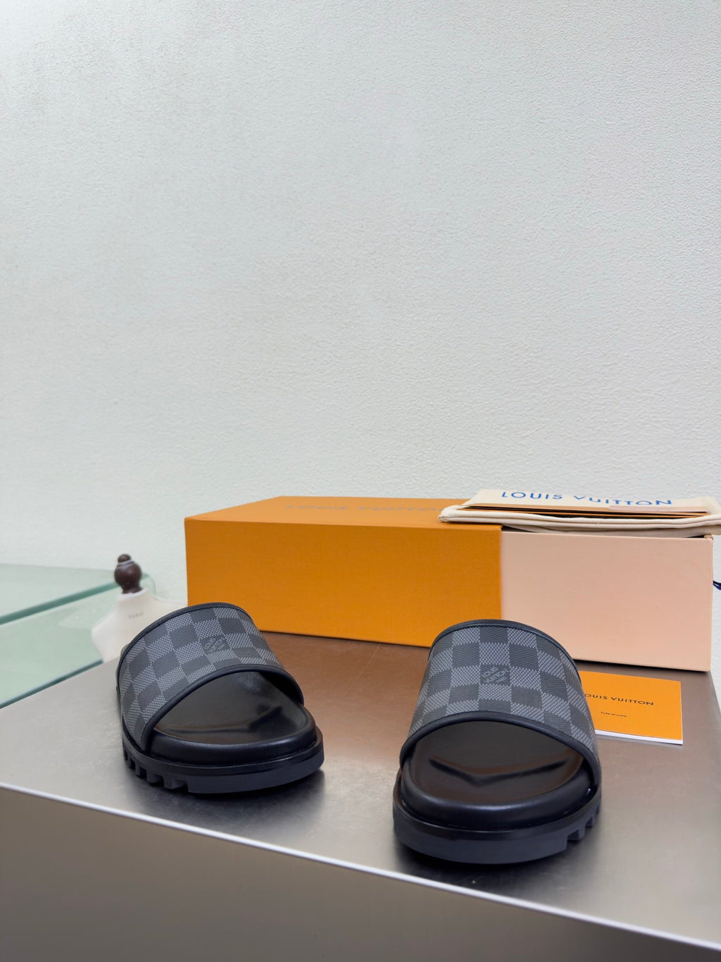 Louis Vuitton slide sandals with dark check-pattern upper and low-profile rubber sole