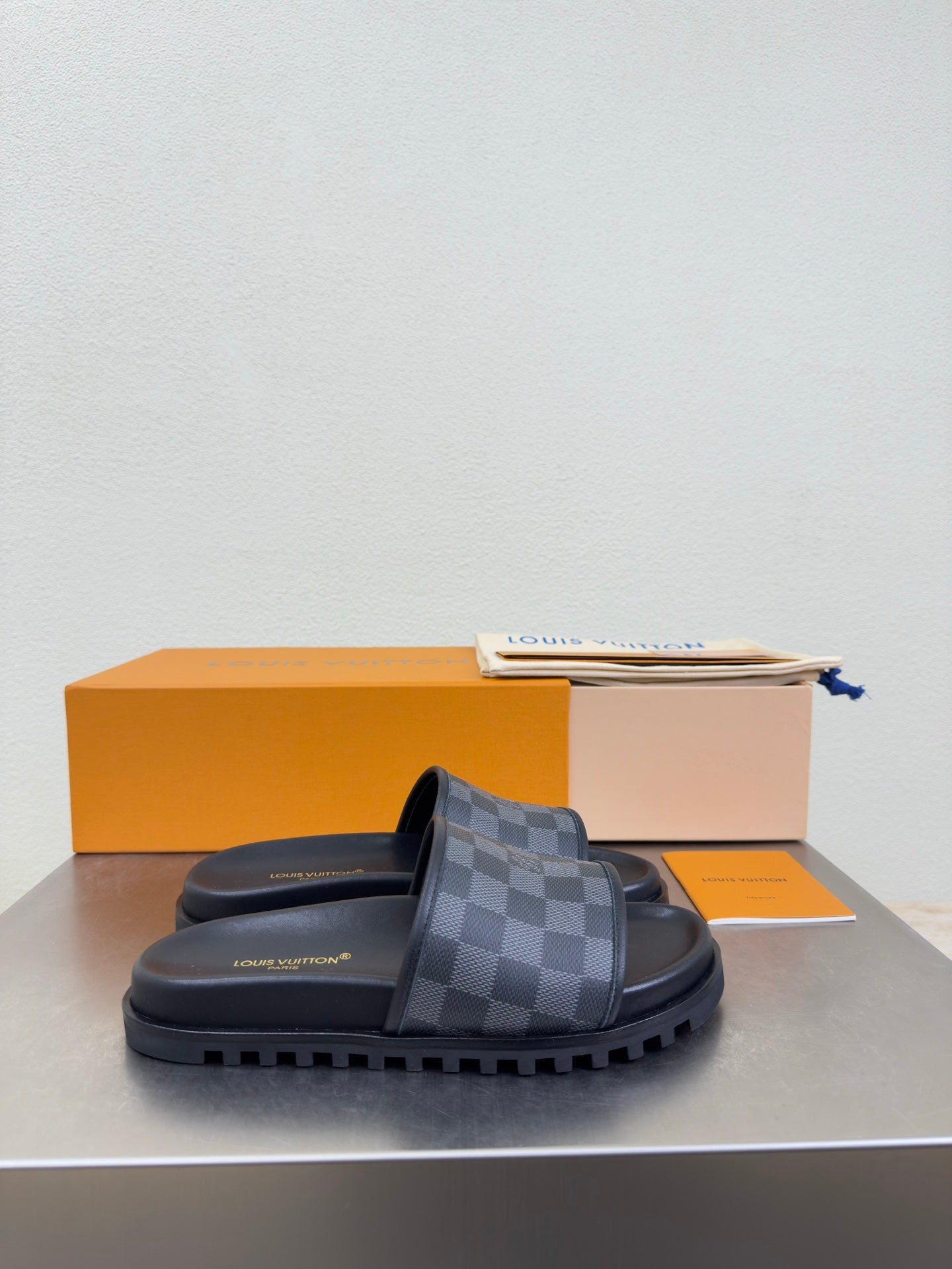 Louis Vuitton slide sandals with dark check-pattern strap and thick rubber sole