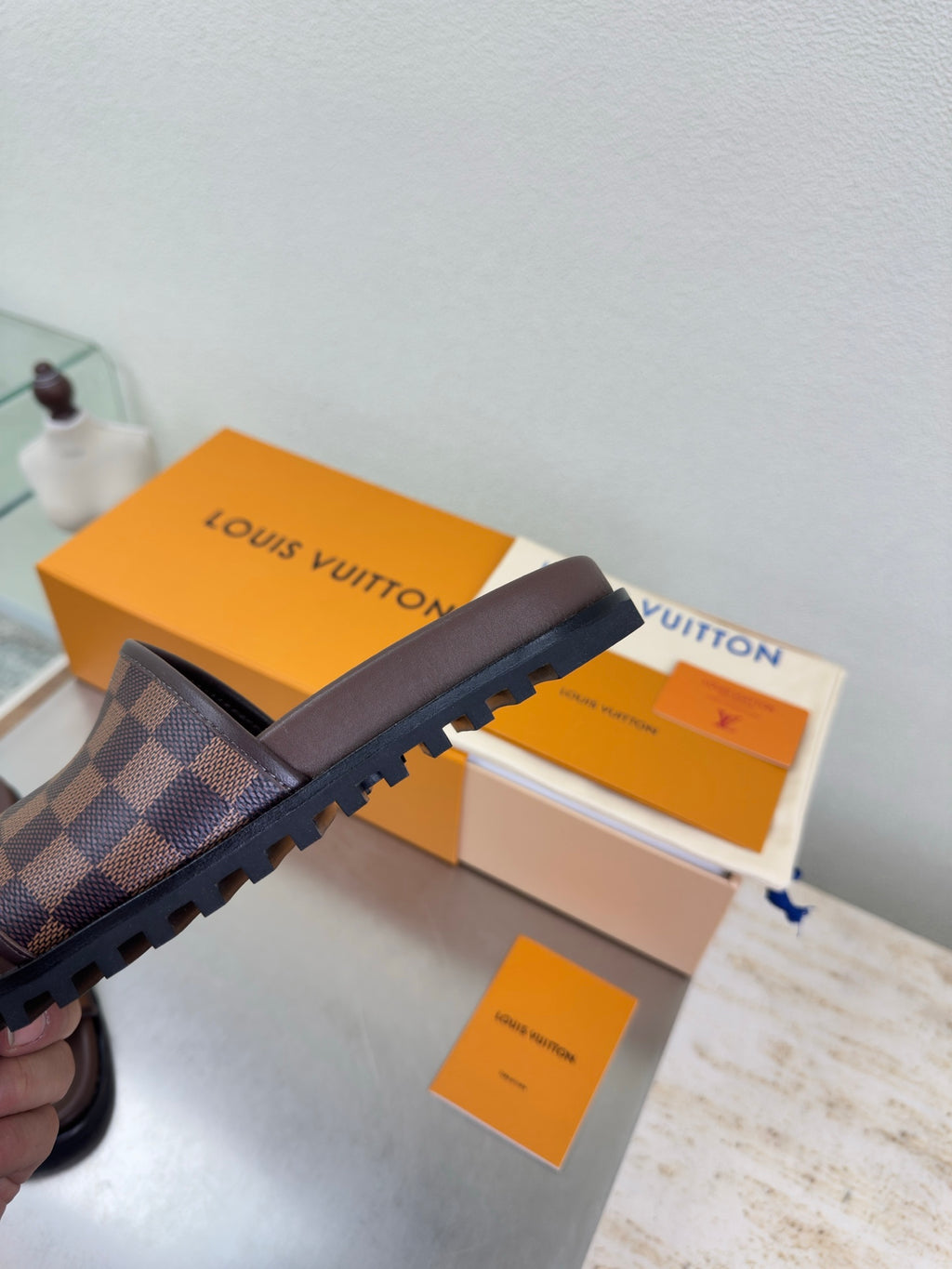 Louis Vuitton damier check slide sandals, brown upper with rugged dark rubber sole.