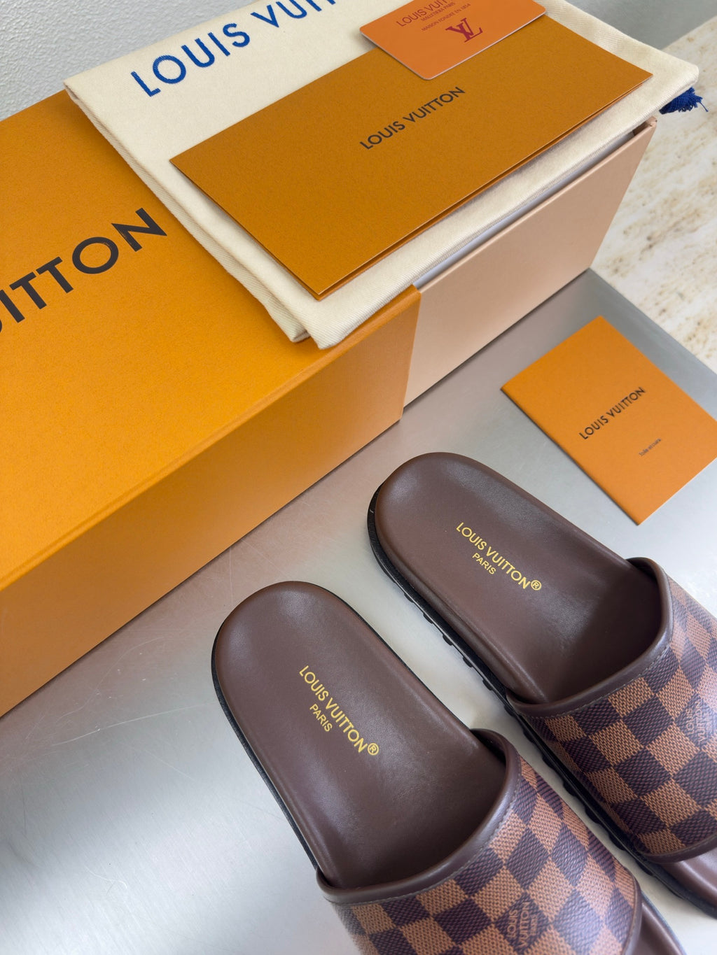 Louis Vuitton damier check slide sandals, brown straps with slip-on silhouette.
