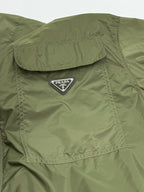 Olive green short-sleeve zip jacket with Prada triangle logo on a chest flap pocket.