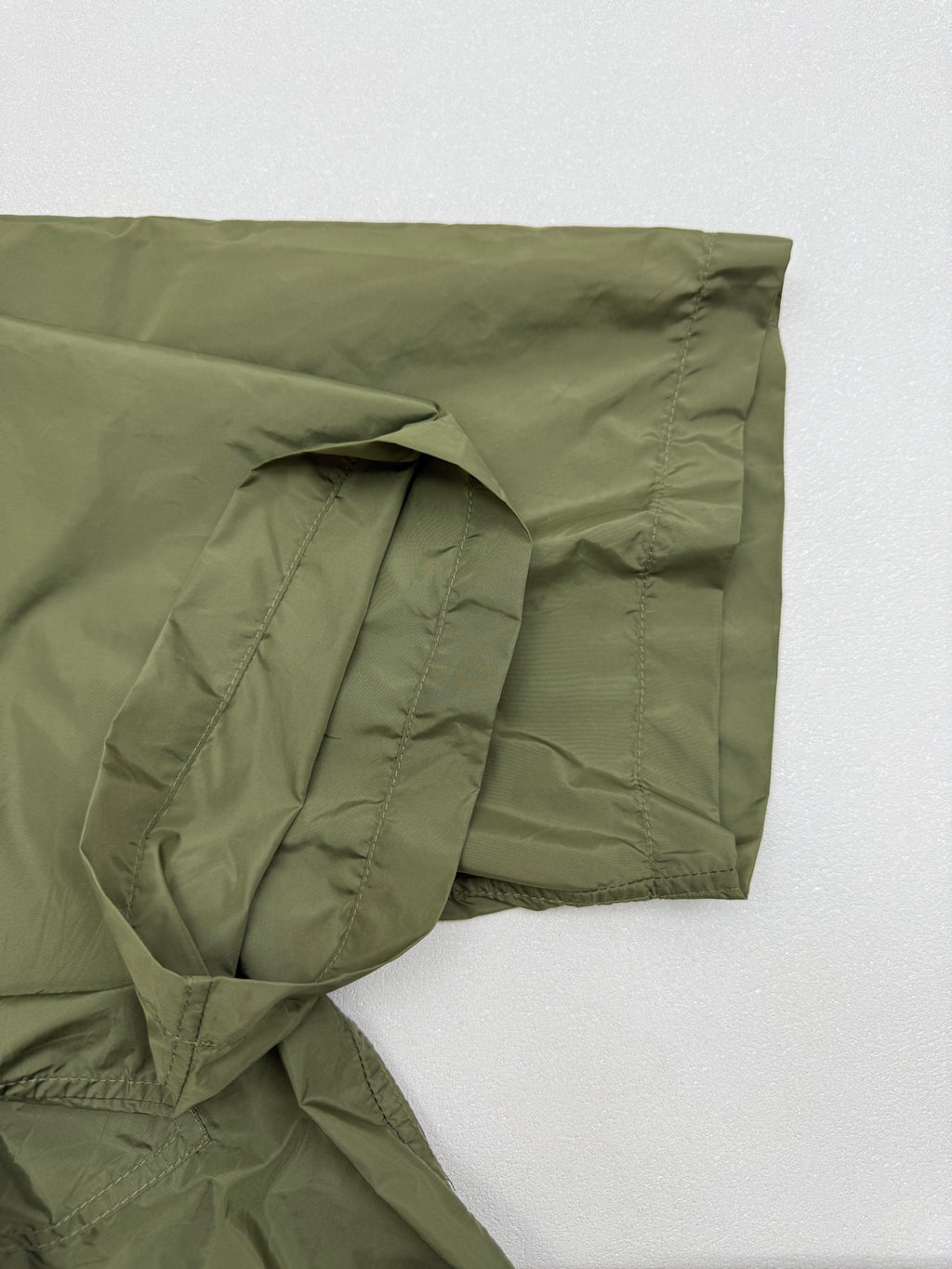 Olive green short-sleeve zip jacket sleeve with gathered fabric and side seam pocket.