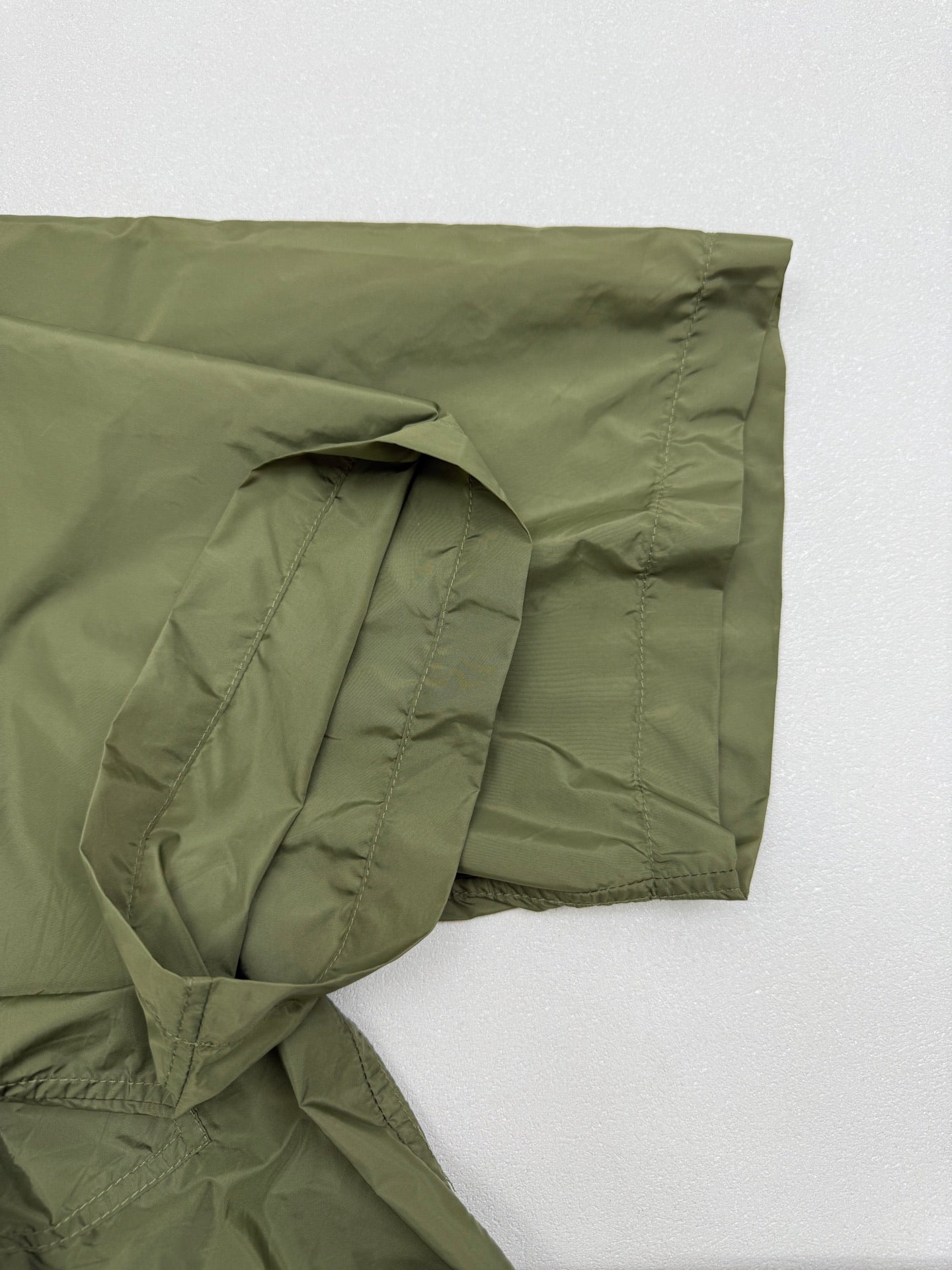 Olive green short-sleeve zip jacket sleeve with gathered fabric and side seam pocket.