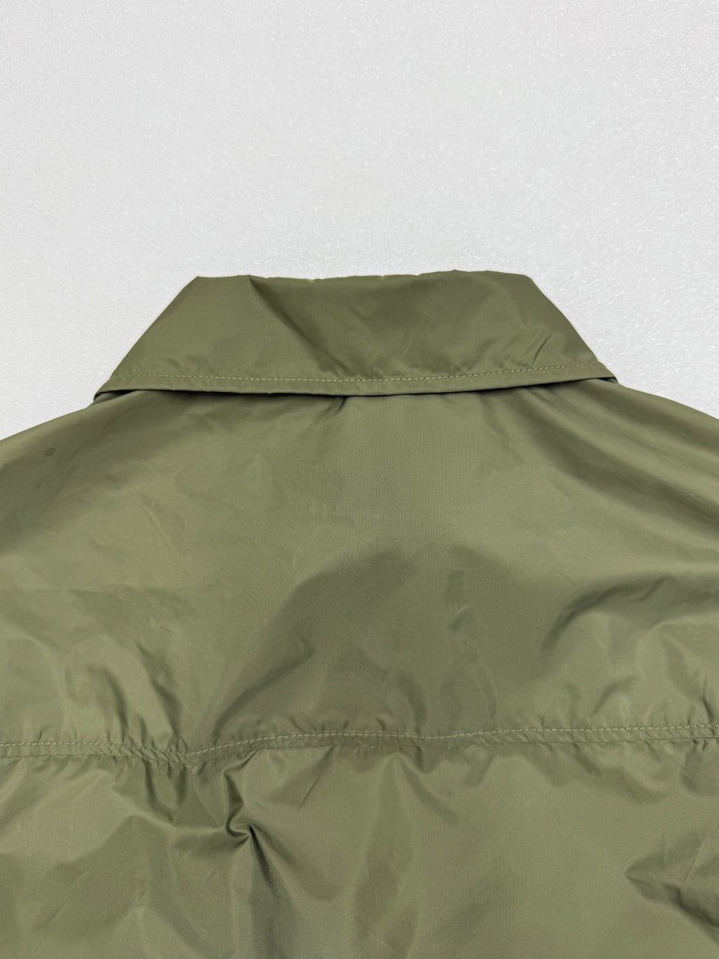 Olive green short-sleeve jacket with back collar and yoke seam detail.