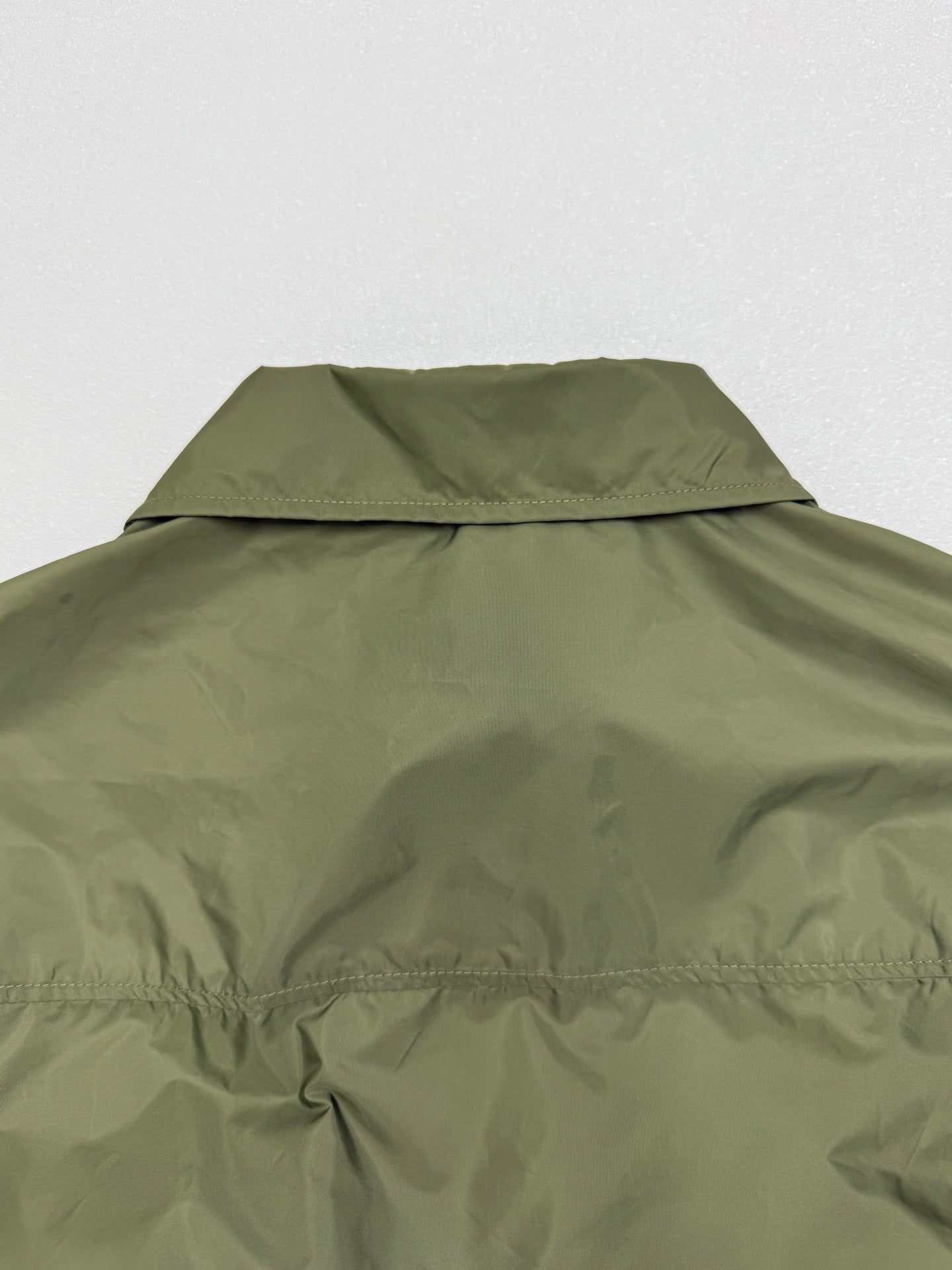 Olive green short-sleeve jacket with back collar and yoke seam detail.