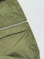 Olive green short-sleeve zip jacket side panel with metal zipper and seam stitching.