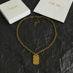 Gold-tone charm necklace with geometric pendant and linked chain.