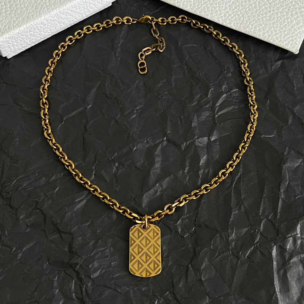 Gold-tone charm pendant necklace with circular linked chain and tag charm.
