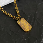 Gold-tone chain necklace with geometric etched drop charm pendant detail.
