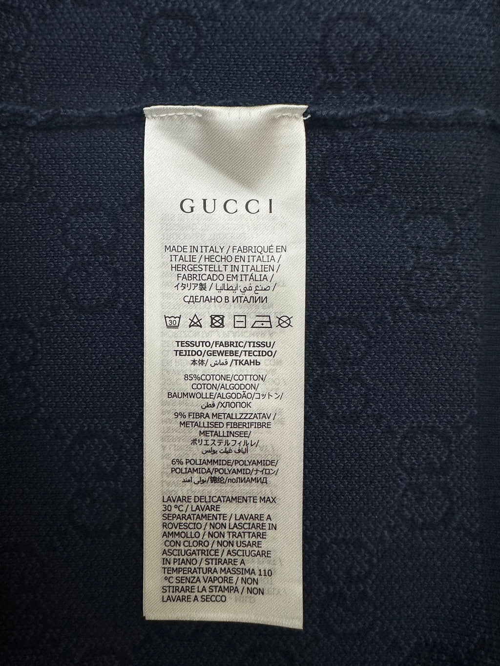 Navy polo shirt care label with GUCCI text and fabric composition