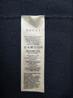 Navy polo shirt care label with GUCCI text and fabric composition