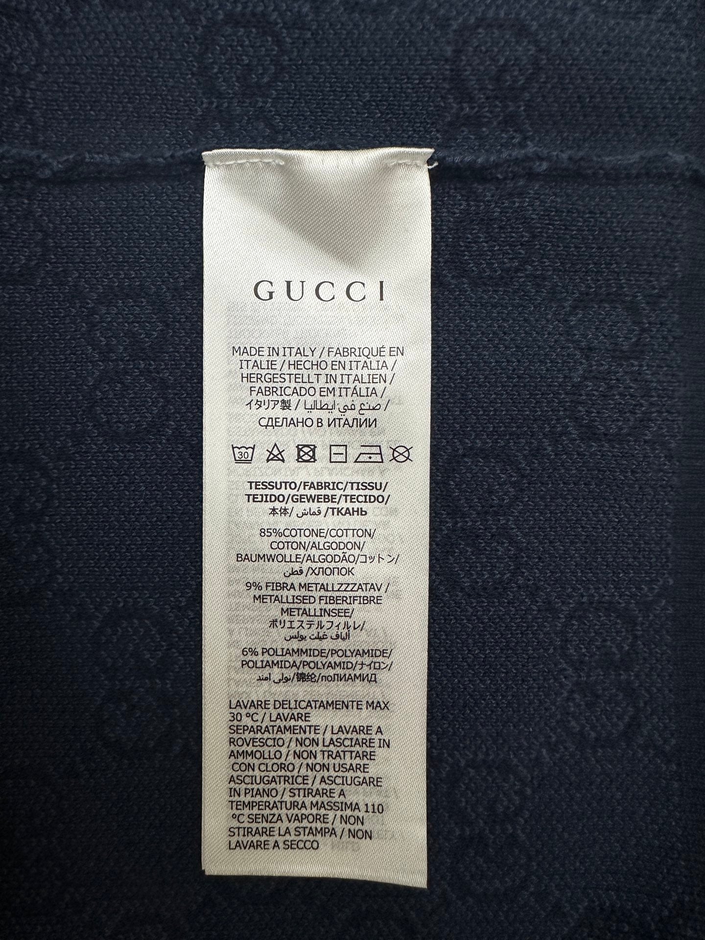 Navy polo shirt care label with GUCCI text and fabric composition