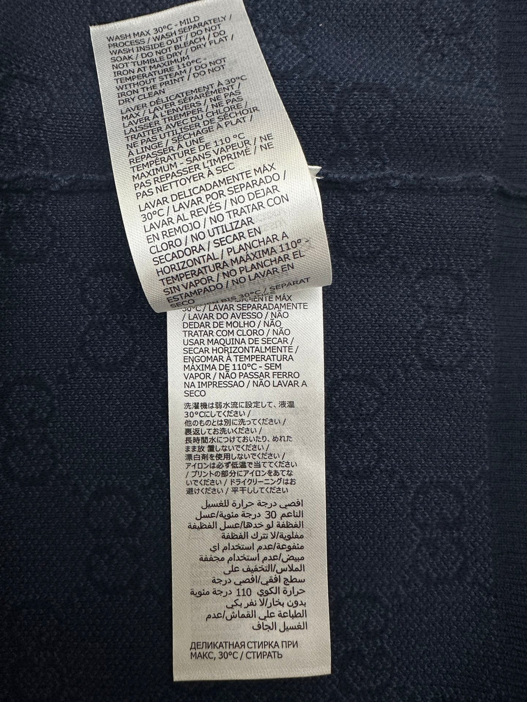 Navy polo shirt care instructions tag with washing symbols and text