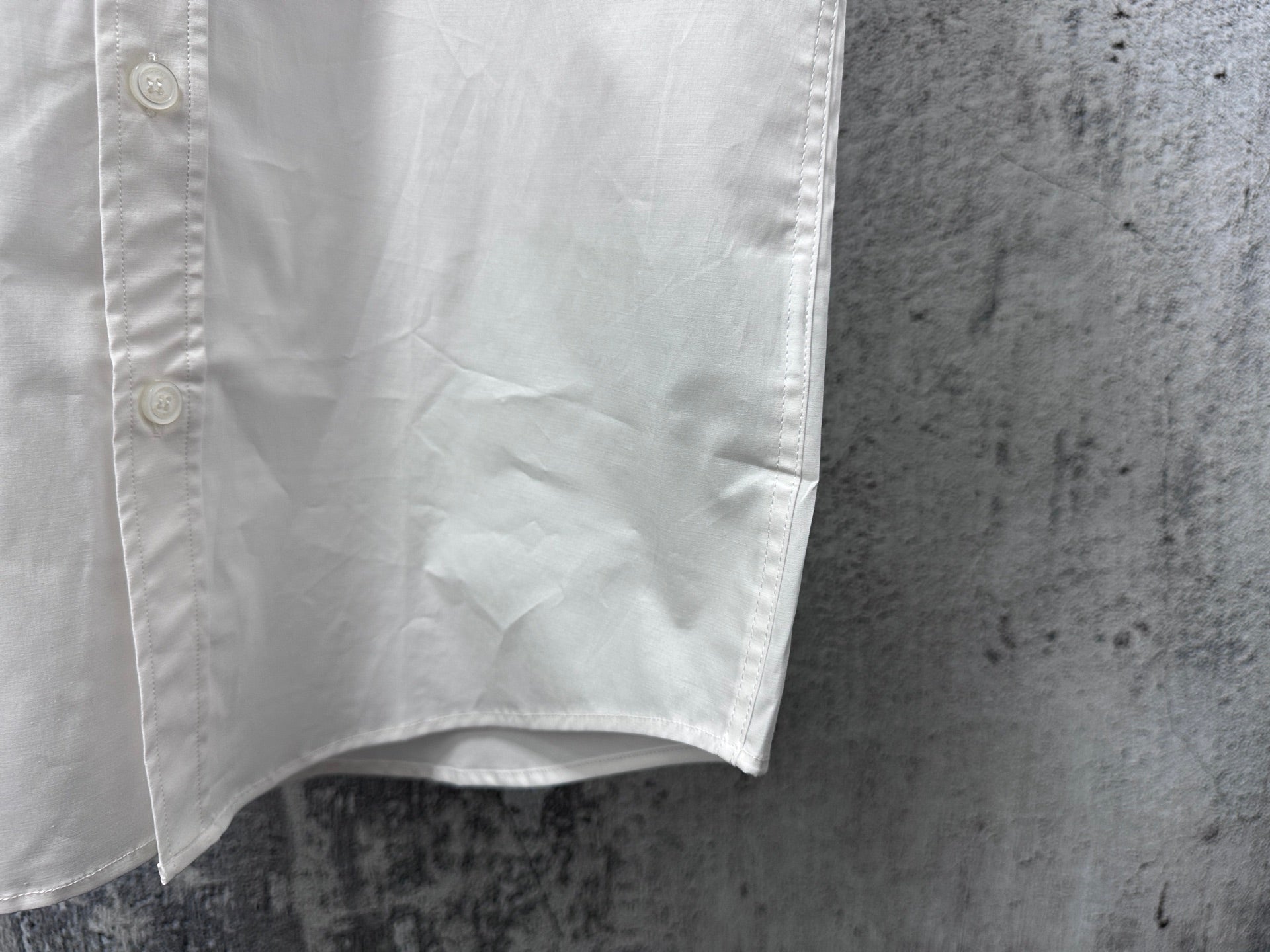 White short-sleeve button-up shirt lower front with curved hem